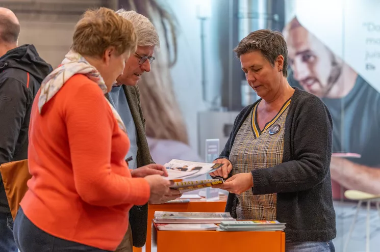 Adviseur toont folder aan 2 bezoekers